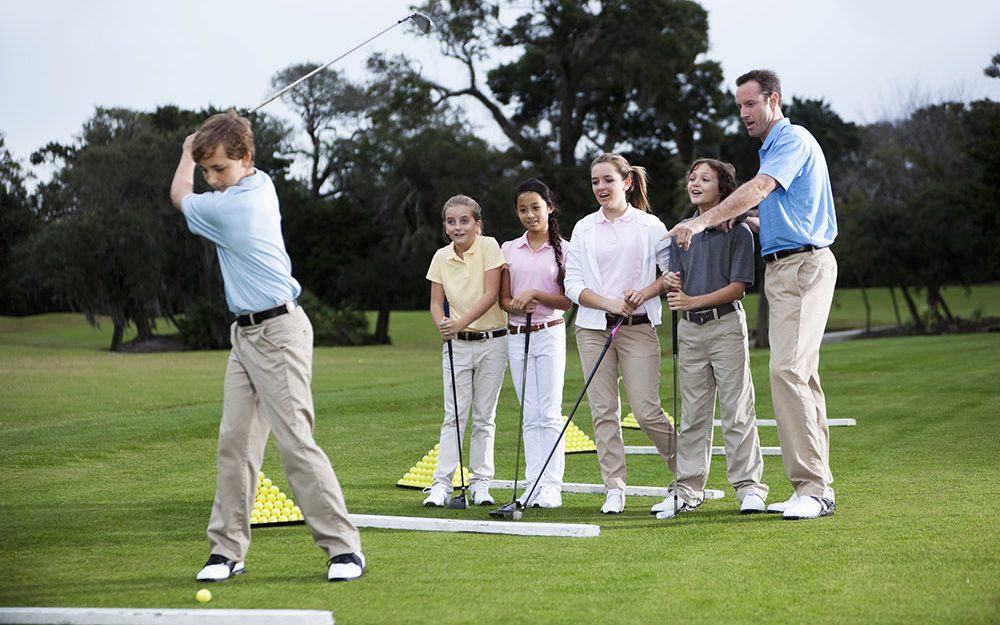 Golf pro teaching group of young players